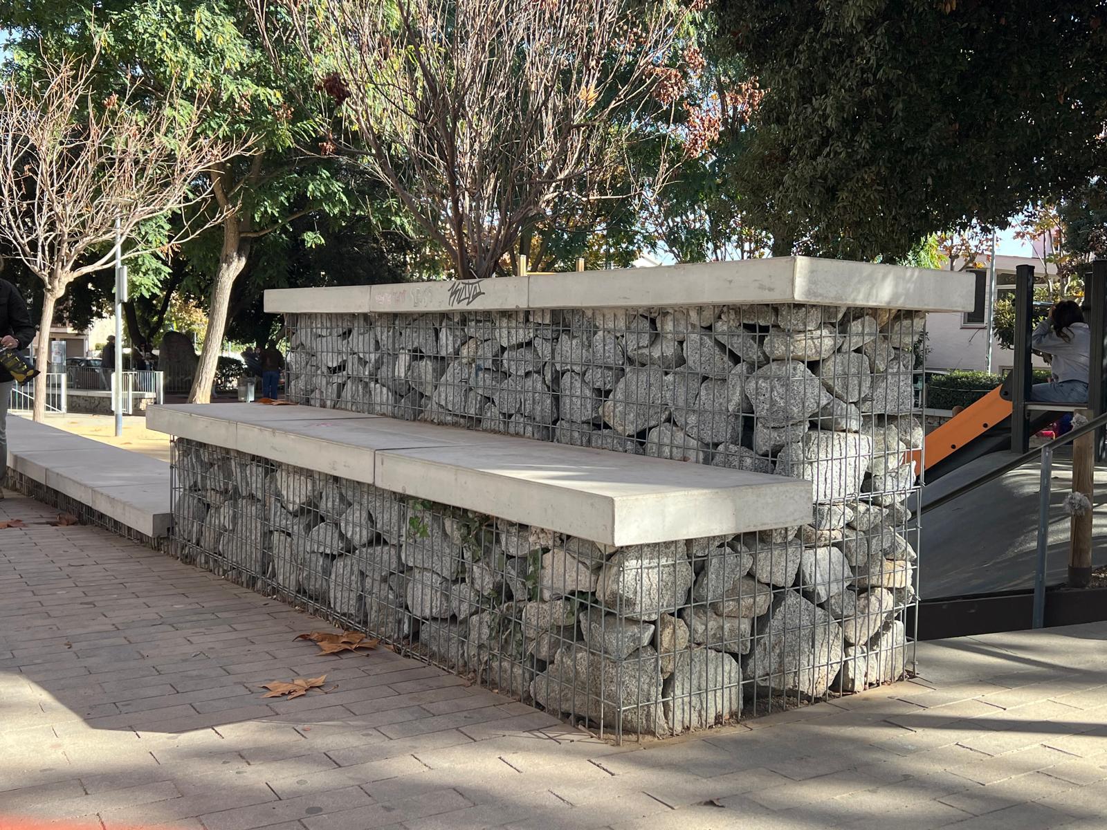 Banco urbano hecho con gaviones de piedra y remate de hormigón en zona peatonal
