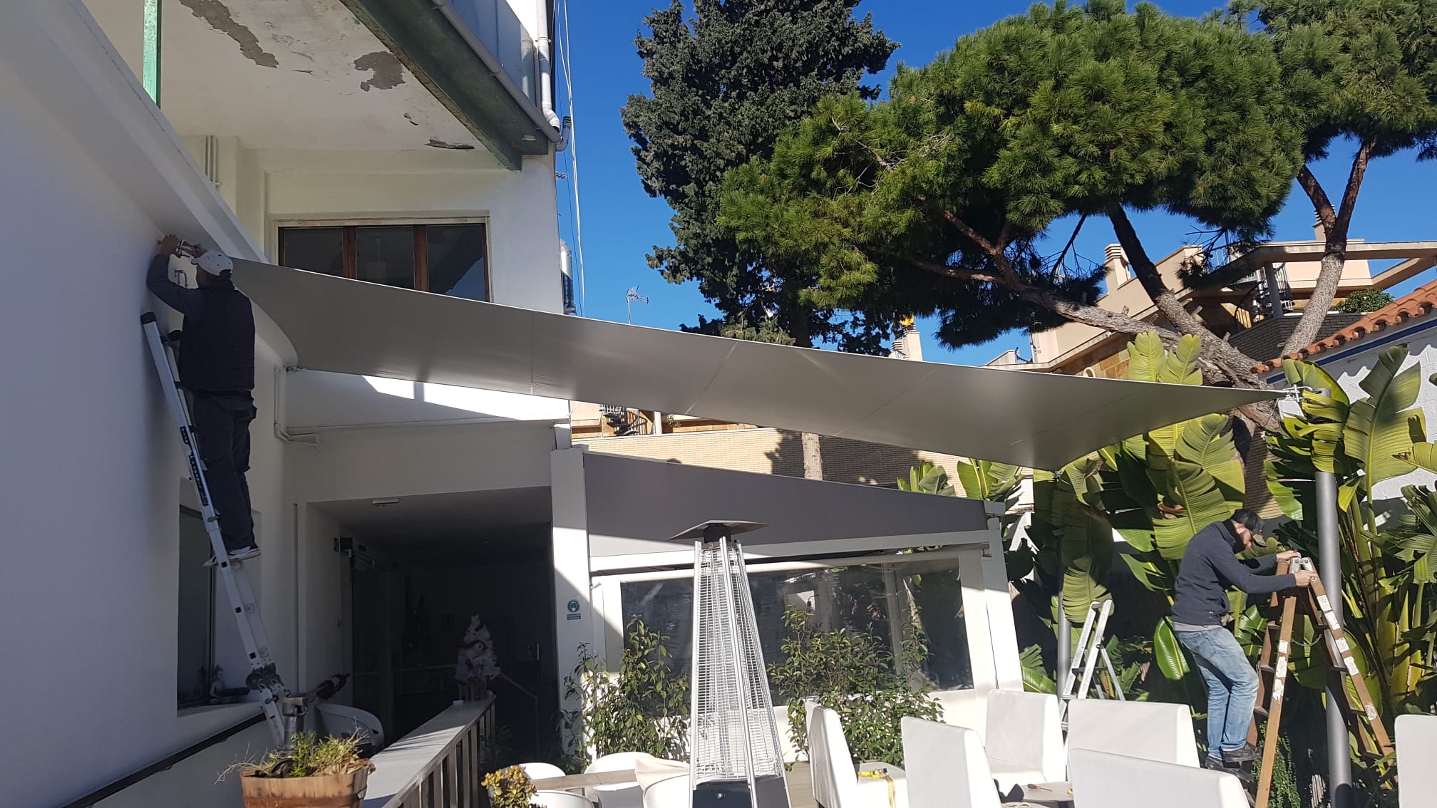 Montaje de sistema retráctil de sombra en terraza de restaurante con instalación en progreso