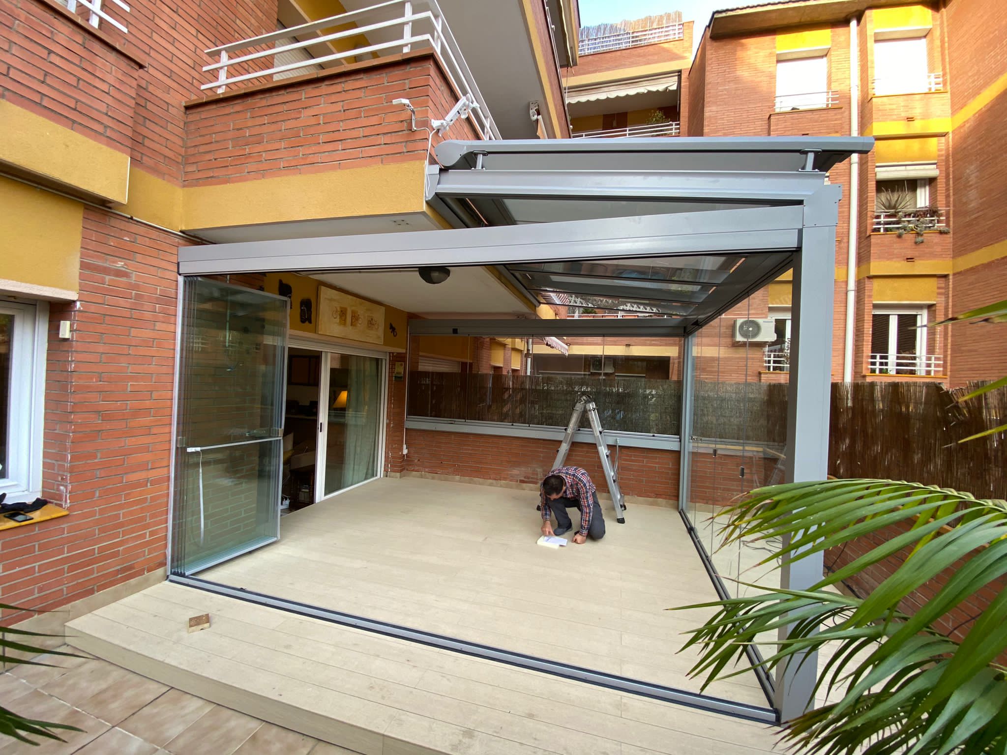 Pérgola de aluminio con cerramiento de vidrio tipo cortavientos para ampliar el uso de la terraza