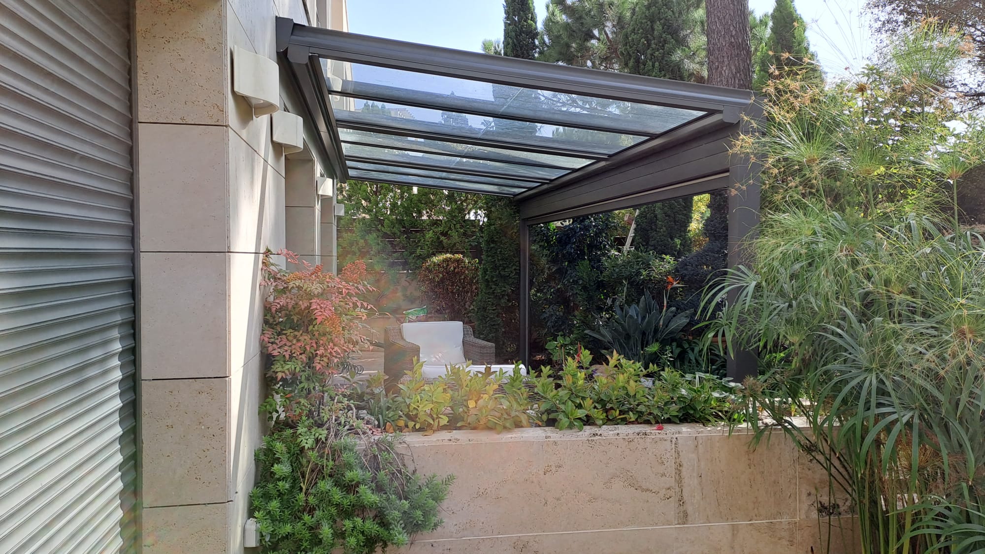 Pérgola adosada a fachada con cubierta transparente para proteger la terraza del sol y la lluvia