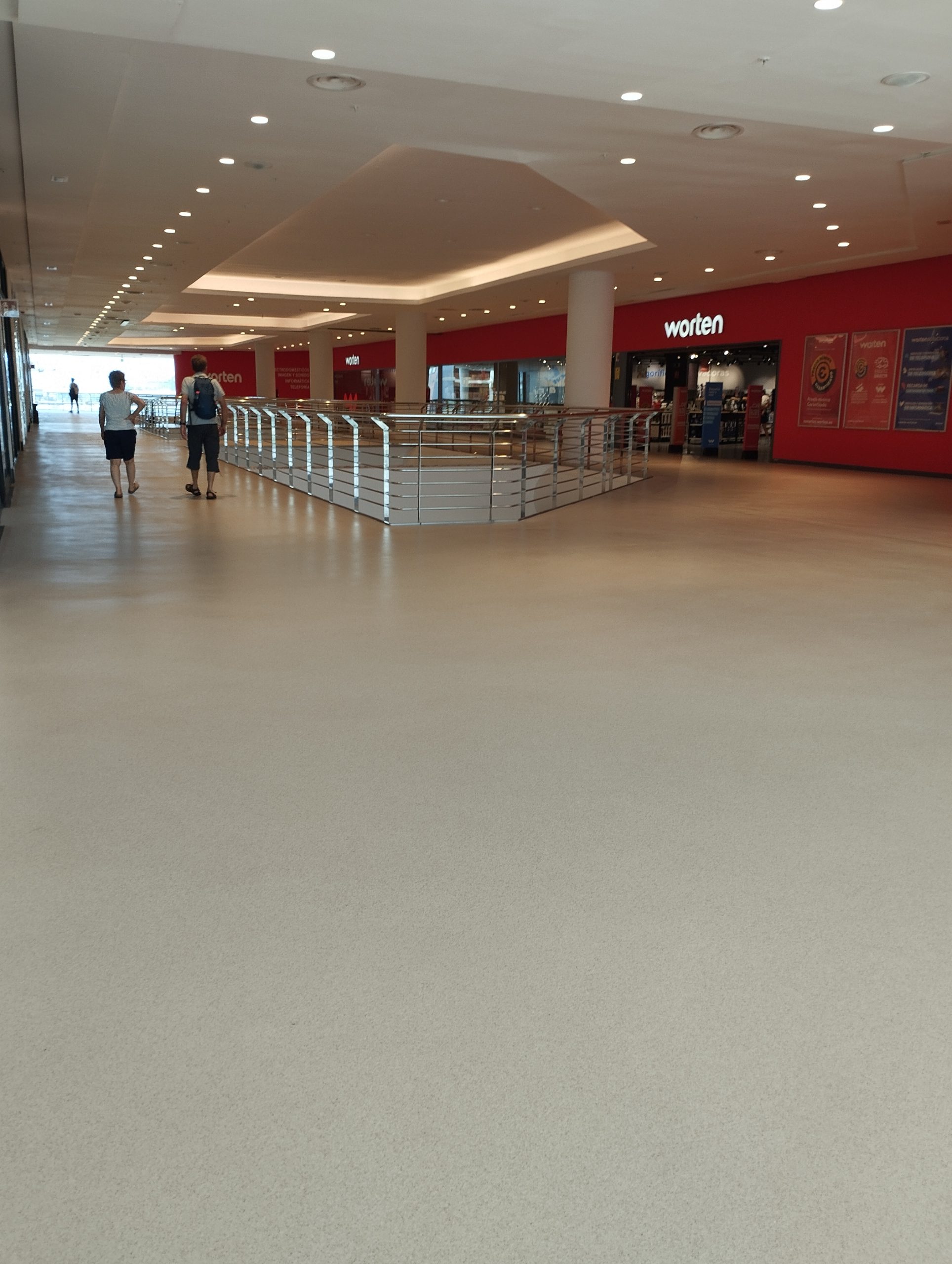 Pavimento continuo en centro comercial o galería comercial con acabado uniforme, limpio y resistente al tránsito diario de personas